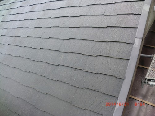 Sloped roof with overlapping gray asphalt shingles arranged in horizontal rows from above view, with a metal edge on the right edge of the image.