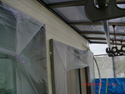 House exterior under renovation with windows and door wrapped in plastic sheeting.