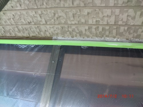 Close-up of a green window frame with glass panes and a textured brick wall above it viewed from inside.