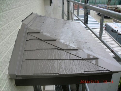 Grey metal roof panels sloped over a building, wet from rain, with scaffolding visible along the side.