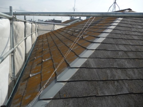 koushin_P1050762-1 | 外壁塗装は神奈川県横浜市の塗装職人 Sloped roof with brown and gray shingles, safety scaffolding visible along left edge, wires running across the roof moments from completion.