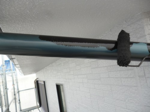 koushin_P1050889-1 | 外壁塗装は神奈川県横浜市の塗装職人 Blue exterior pipe with peeling paint and a black foam insulation sleeve, mounted under an overhang on a white-brick exterior wall.