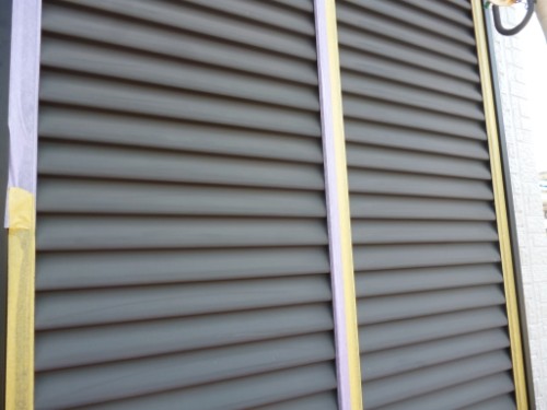 koushin_P1050896-1 | 外壁塗装は神奈川県横浜市の塗装職人 Close-up of brown louvered shutters on a building, with yellow painter's tape along the edges.