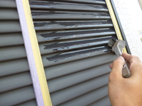 koushin_P1050898-1 | 外壁塗装は神奈川県横浜市の塗装職人 Person painting exterior shutter slats with a gray brush, masking tape along the edges visible on the frame