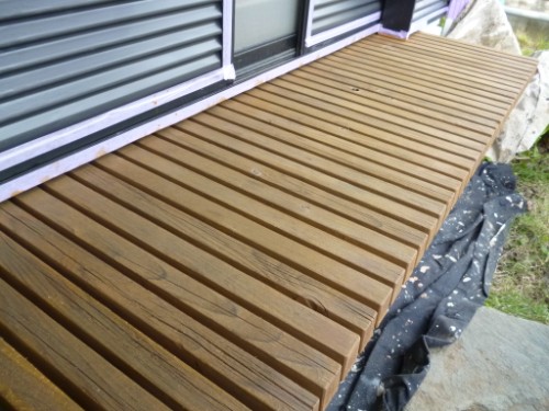 koushin_P1050911-1 | 外壁塗装は神奈川県横浜市の塗装職人 Brown stained wooden deck slats running parallel along the house exterior.
