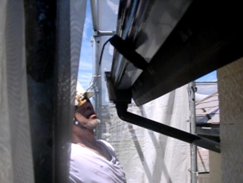 Construction worker in a hard hat inspects a beam between scaffolding on a construction site.