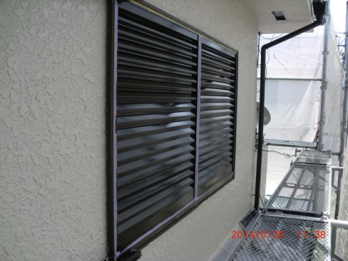 Exterior wall with vented louvered windows along a scaffolded building exterior, likely during construction or renovation.