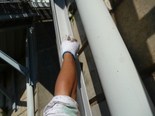 Worker's gloved arm resting on a metal railing during exterior maintenance on a building balcony edge