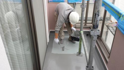 koushin_20140125top2 | 外壁塗装は神奈川県横浜市の塗装職人 Construction worker in a hard hat and gloves smoothing wet concrete on a small balcony with scaffolding nearby.