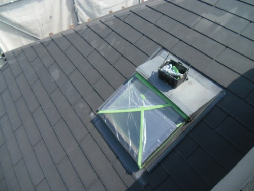 koushin_CIMG2580-1 | 外壁塗装は神奈川県横浜市の塗装職人 Rectangular skylight on a dark metal roof, covered with plastic and green tape; a small toolbox sits nearby.