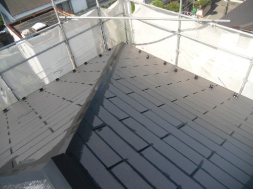koushin_CIMG2604-1 | 外壁塗装は神奈川県横浜市の塗装職人 Top-down view of a sloped roof covered in dark shingles, surrounded by metal scaffolding.