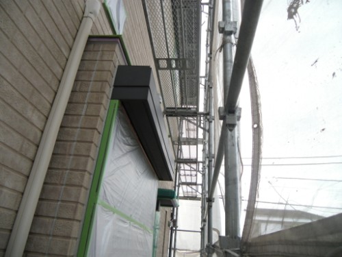 koushin_CIMG2609-1 | 外壁塗装は神奈川県横浜市の塗装職人 Side view of a brick building under construction with metal scaffolding and plastic-covered windows along the exterior.