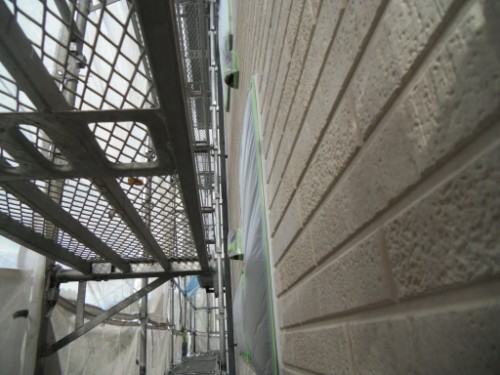 koushin_CIMG2611-1 | 外壁塗装は神奈川県横浜市の塗装職人 Narrow alley between a brick wall and metal construction scaffolding, viewed from ground level with blue tarps and netting along the wall.