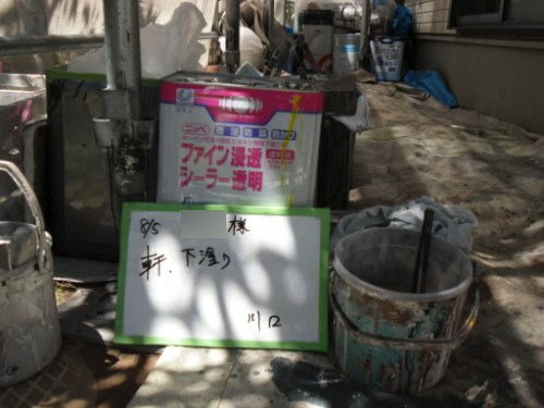 koushin_CIMG2621-1 | 外壁塗装は神奈川県横浜市の塗装職人 Construction site corner with a pink/blue poster behind a green-framed whiteboard containing handwritten Japanese text; nearby buckets.