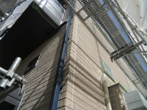 koushin_CIMG2631 | 外壁塗装は神奈川県横浜市の塗装職人 Corner of a brick building under construction with metal scaffolding and a blue downspout running along the wall.
