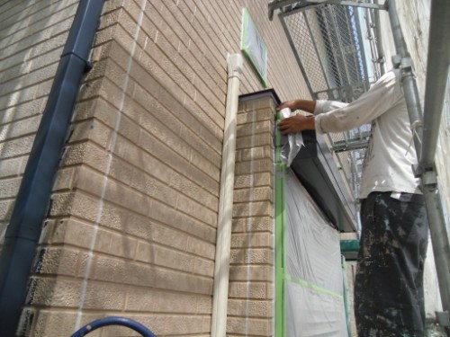 koushin_CIMG2644 | 外壁塗装は神奈川県横浜市の塗装職人 Worker on scaffolding painting exterior door frame, masking area with tape and plastic sheeting.