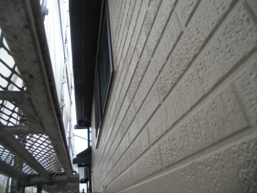 koushin_CIMG2650 | 外壁塗装は神奈川県横浜市の塗装職人 Narrow alley along a beige brick building, seen from ground level with a metal catwalk on the left.