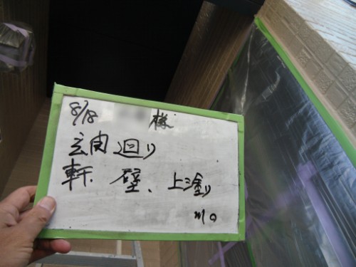 koushin_CIMG2675 | 外壁塗装は神奈川県横浜市の塗装職人 Hand holding a small whiteboard with a green frame and handwritten Japanese notes, near a taped-off construction area.