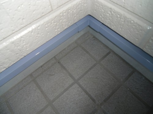 koushin_CIMG2677 | 外壁塗装は神奈川県横浜市の塗装職人 Corner of a tiled floor meeting two walls with light gray grout lines and a blue baseboard trim along the base of the walls