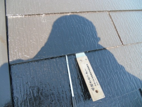 koushin_CIMG2680 | 外壁塗装は神奈川県横浜市の塗装職人 Shadow of a person on a dark shingled roof beside a small wooden label with writing.