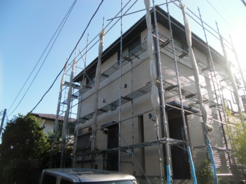 koushin_CIMG2690 | 外壁塗装は神奈川県横浜市の塗装職人 Two-story house surrounded by metal scaffolding for exterior construction on a sunny day, with a parked van nearby