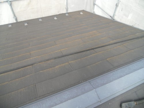 koushin_CIMG2869-1 | 外壁塗装は神奈川県横浜市の塗装職人 Dark brown roof shingles laid in neat rows on a flat roof, with a metal edge at the front and the interior of a temporary shelter visible around the perimeter.