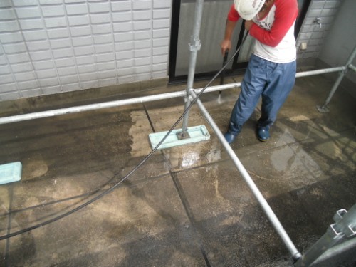 koushin_CIMG2880-1 | 外壁塗装は神奈川県横浜市の塗装職人 Maintenance worker on a scaffolded rooftop, operating a long cleaning wand over a wet surface.