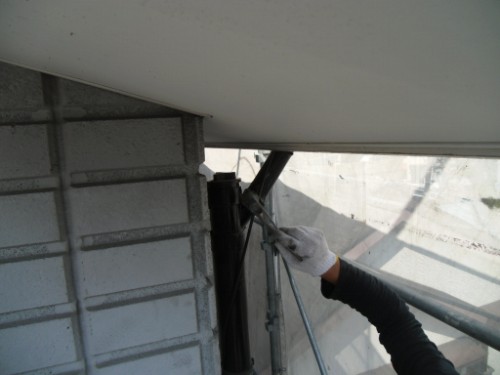 koushin_CIMG2930-1 | 外壁塗装は神奈川県横浜市の塗装職人 Worker in a glove tightens a metal bracket under a balcony from scaffolding.