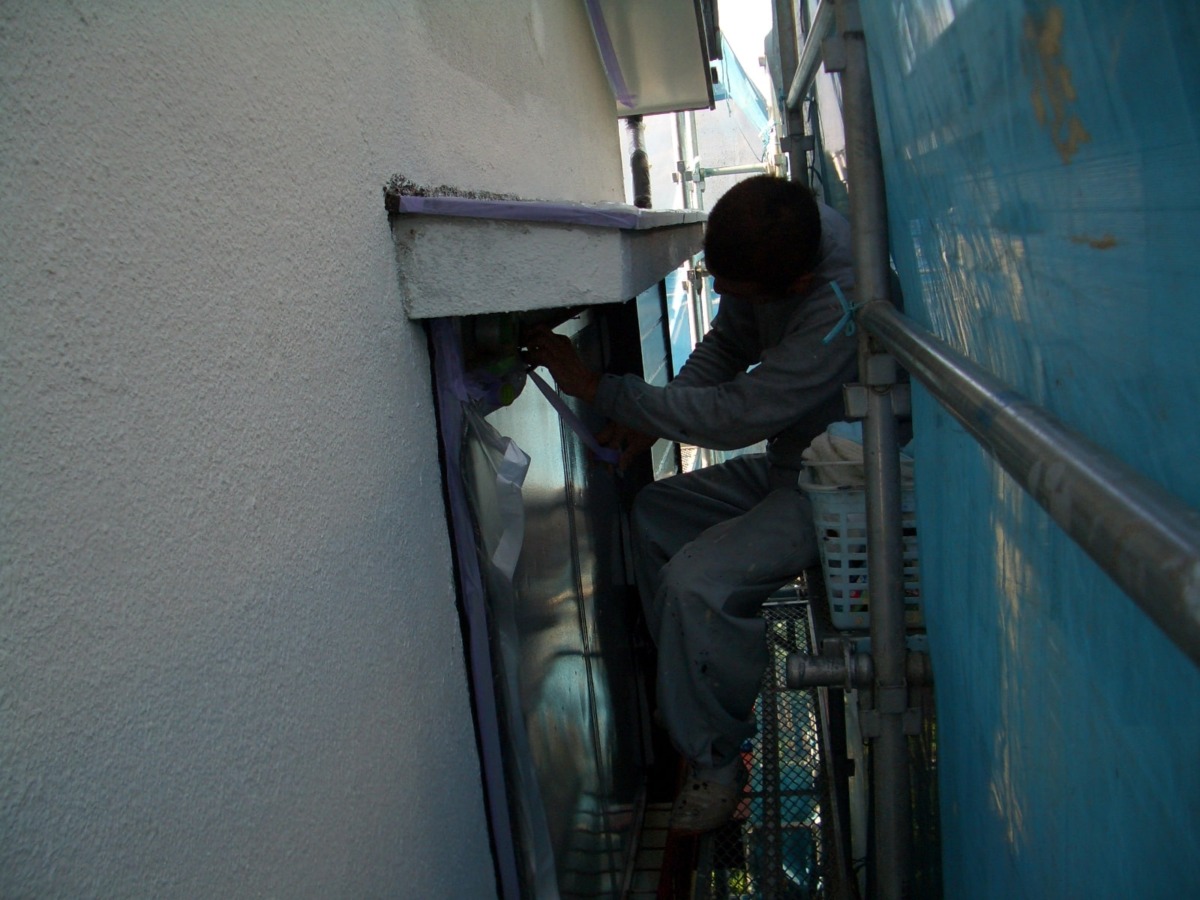 Construction worker on scaffolding repairs or installs a window on a narrow exterior wall of a building