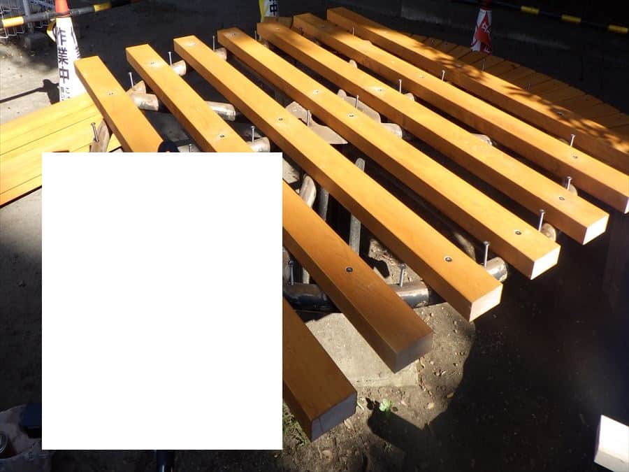 Row of orange-brown wooden planks bolted to metal supports at a construction site.