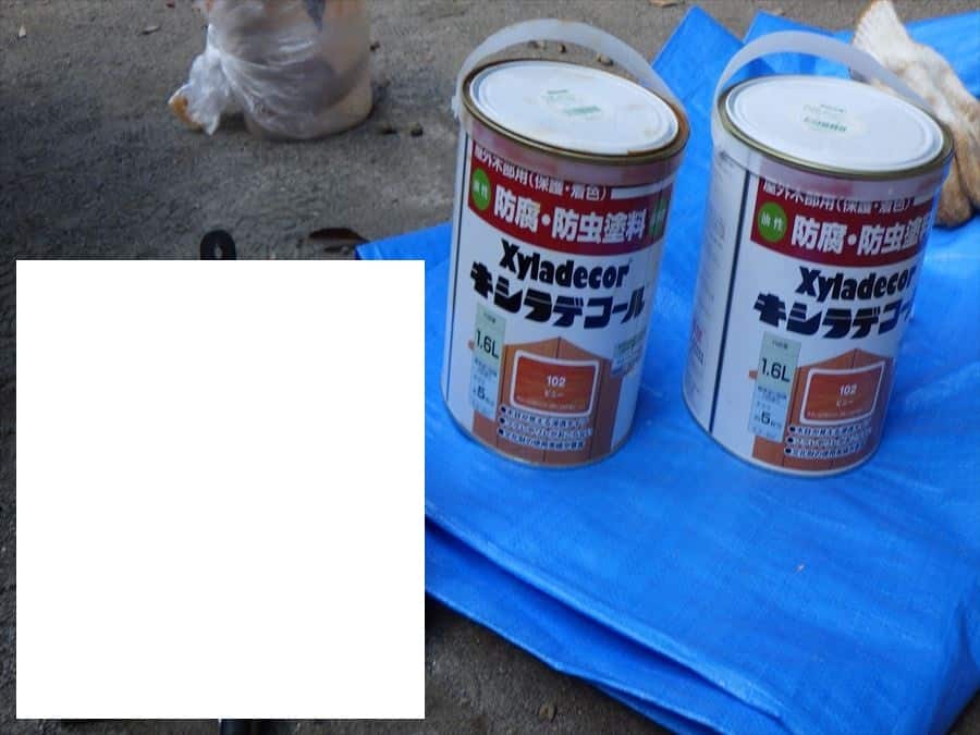 Two Xyladecor paint cans on a blue tarp outdoors, ready for use.