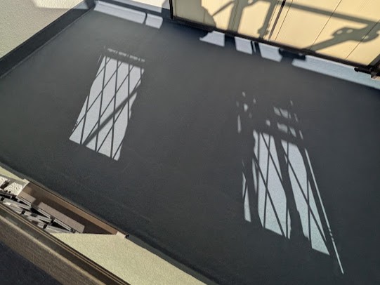 11-balcony-finish | 外壁塗装は神奈川県横浜市の塗装職人 Shadows of metal railing cast across a dark balcony floor, with window bars visible on the left side.