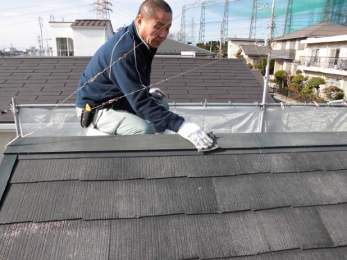 屋根の雨押さえを研磨する職人
