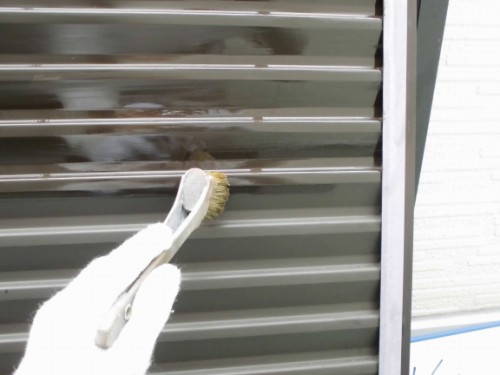 雨戸へ刷毛でプライマーを下塗りする様子