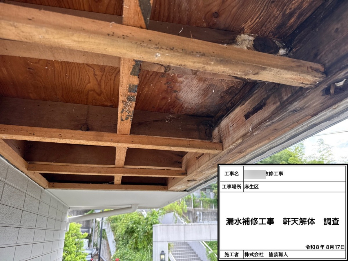 Exposed wooden ceiling joists and framing under construction, with a Japanese work label indicating leak-repair and inspection work