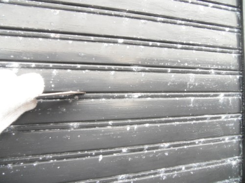 koushin_CIMG1281-1 | 外壁塗装は神奈川県横浜市の塗装職人 Gloved hand pulling a latch on a dark metal rolling shutter with snow on it.