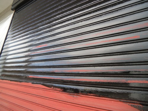 koushin_CIMG1301-1 | 外壁塗装は神奈川県横浜市の塗装職人 Close-up of a black corrugated roll-up shutter with a red lower section and a glossy finish, angled view