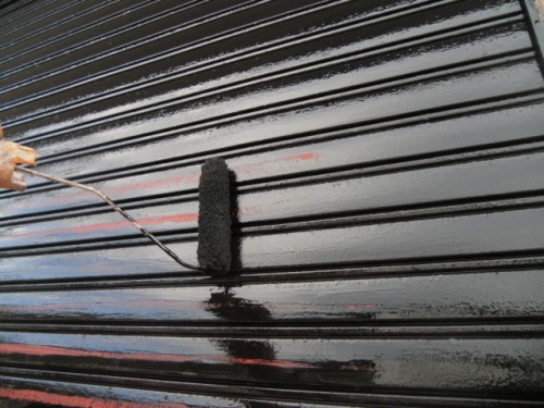 koushin_CIMG1302-1 | 外壁塗装は神奈川県横浜市の塗装職人 Close-up of a paint roller applying glossy black paint to horizontal metal slats.