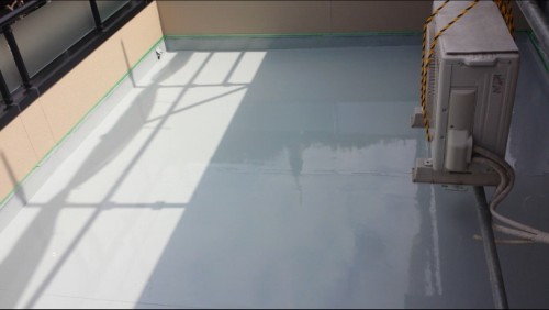 koushin_bousuisou1 | 外壁塗装は神奈川県横浜市の塗装職人 Rooftop terrace with an exterior air conditioner on the right, gray waterproof floor, and shadows from a railing on the left.