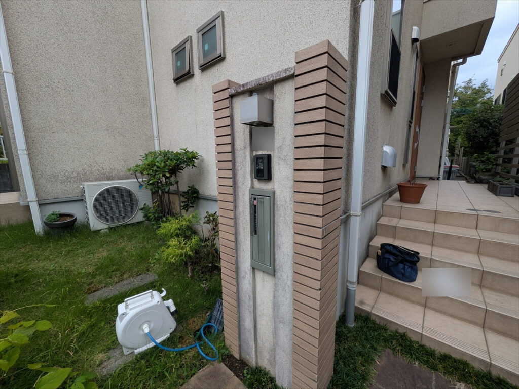 門柱、玄関階段、外壁、室外機が並ぶ建物まわり
