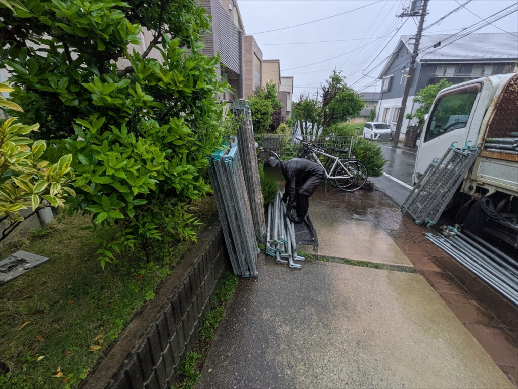 敷地前で足場部材を扱う作業者と搬入車両
