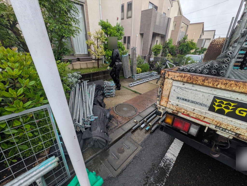 足場部材を積んだトラックと敷地前の部材