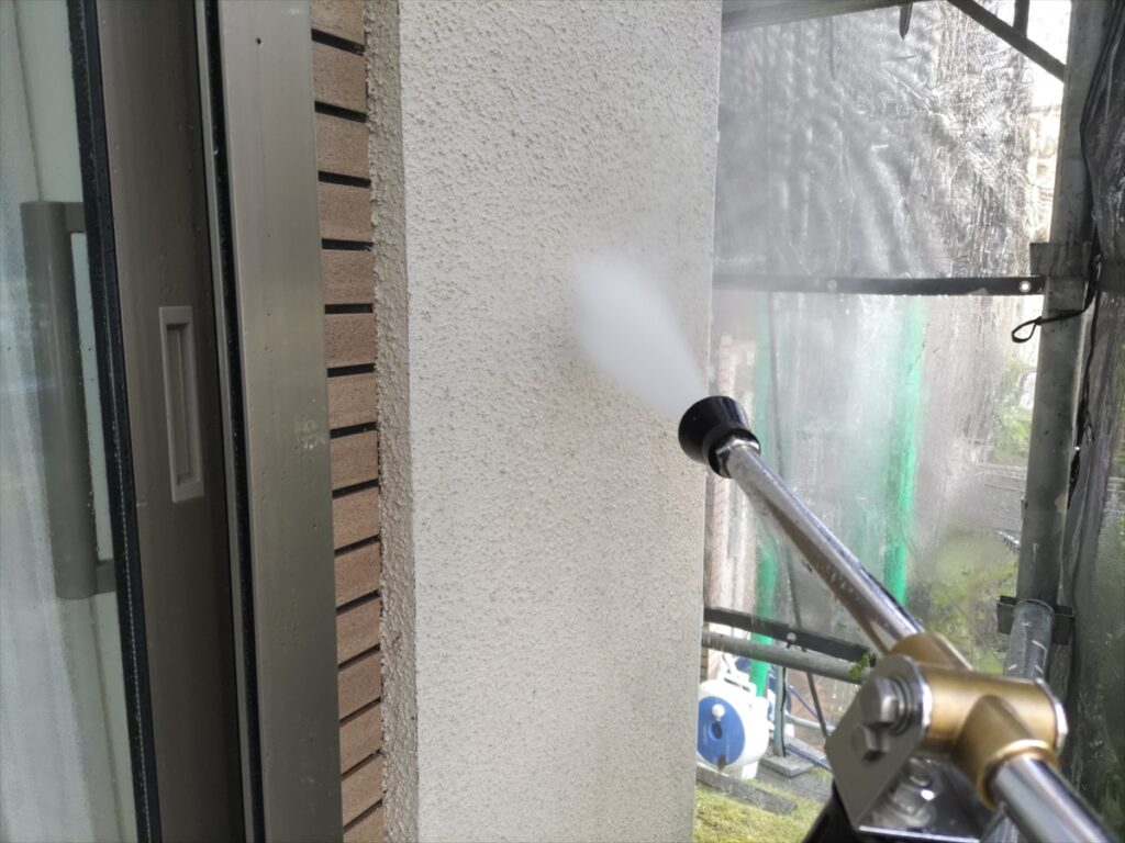 窓際の外壁へ洗浄ノズルで水を当てる様子