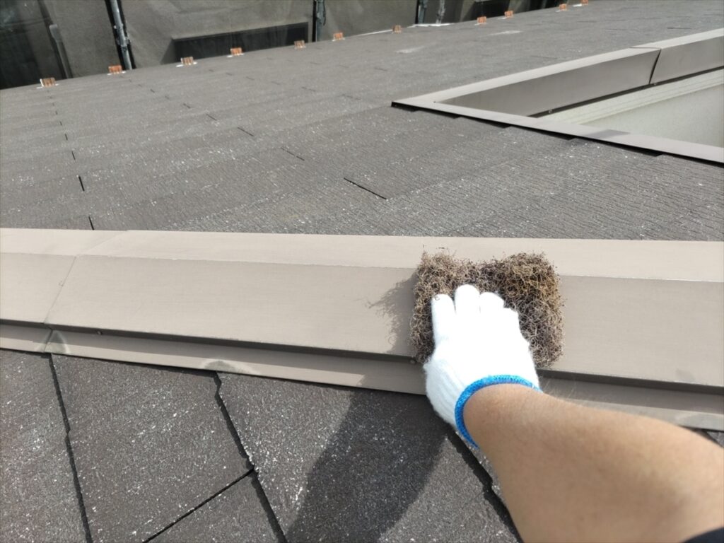 研磨材で棟板金の表面をこする手元