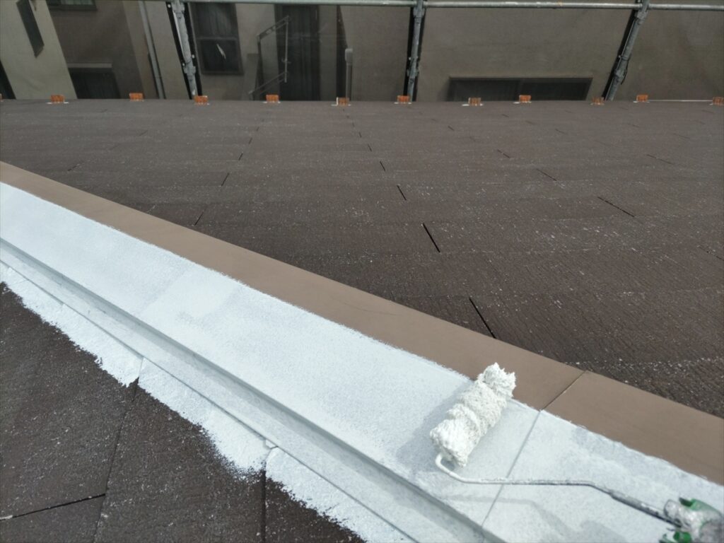 棟板金をローラーで白く下塗りする手元