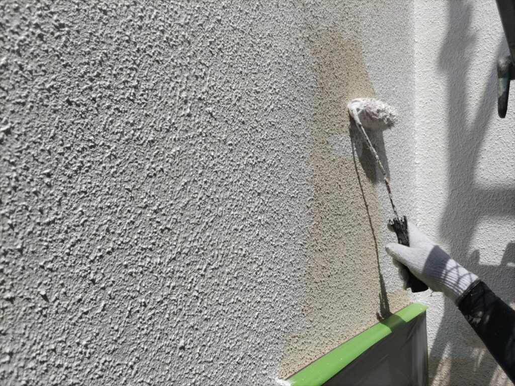 粒状の凹凸がある壁へ白い材料を塗るローラー