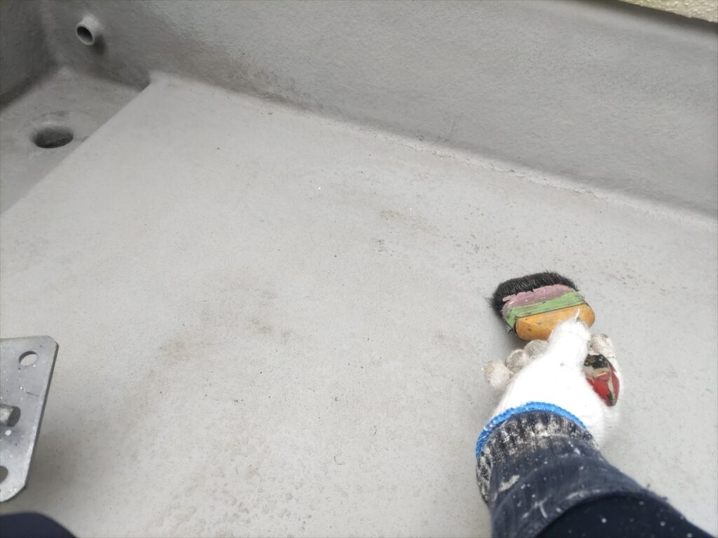 ベランダ床を刷毛で掃く手元