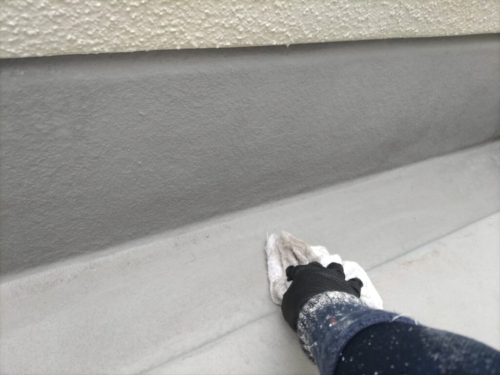 立ち上がりに沿って床面を布で拭く様子