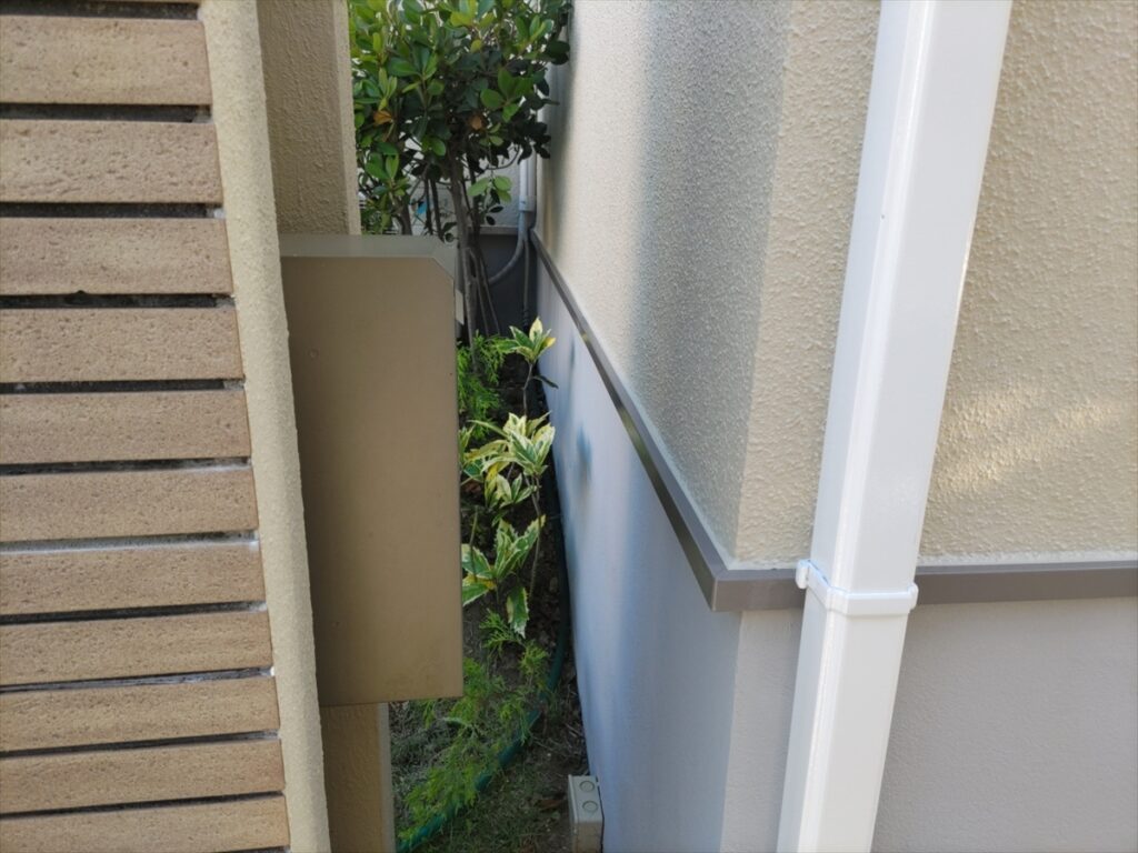 白い縦樋と水切りの下の灰色の基礎