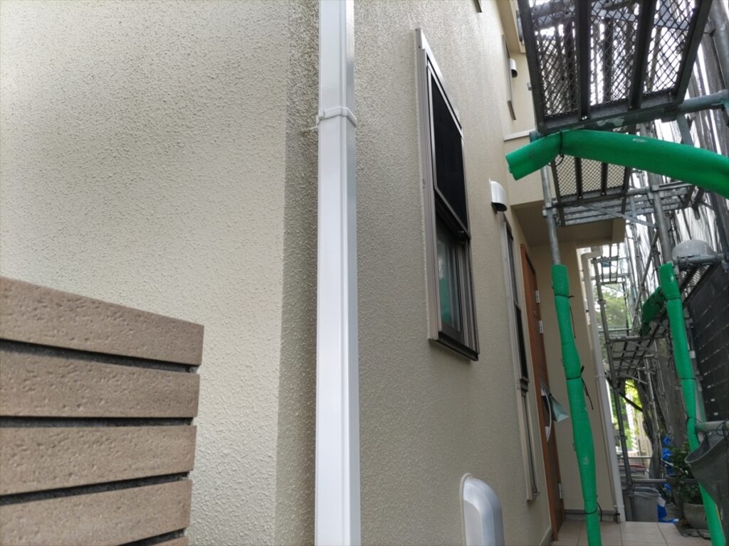 窓と白い縦樋に沿って仕上がった外壁
